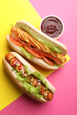 Delicious hot dogs with lettuce and sauces on color background, flat layの写真素材