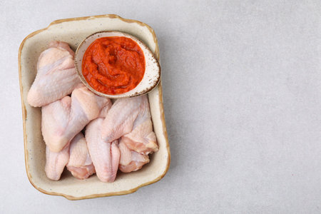 Fresh marinade and raw chicken in baking dish on light table, top view. Space for textの写真素材
