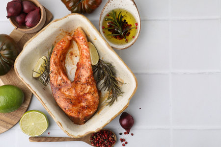 Freshly cooked fish and other products on white tiled table, flat lay. Space for text