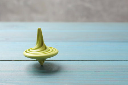 Bright spinning top on light blue wooden table, closeup. Space for textの写真素材