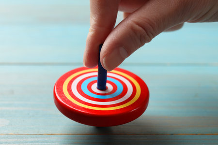 Woman playing with bright spinning top at light blue wooden table, closeupの写真素材