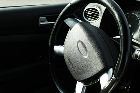 Black steering wheel in car, closeup. Space for text