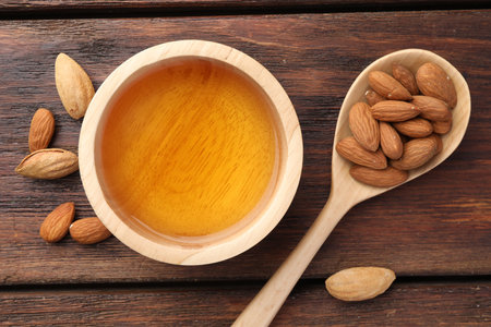 Almond butter in bowl, nuts and spoon on wooden table, flat layの写真素材