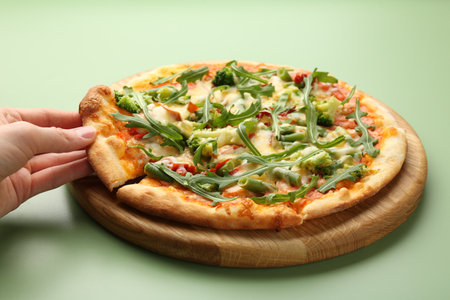 Woman taking a piece of delicious vegetarian pizza at green table, closeupの写真素材