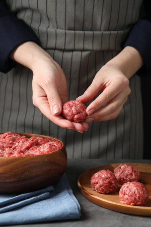 Woman making meatball from ground meat at gray table, closeupの写真素材