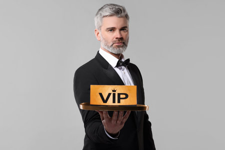 Handsome man holding tray with VIP sign on light grey backgroundの写真素材
