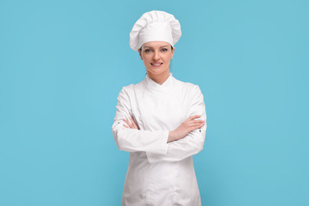 Happy chef in uniform on light blue backgroundの写真素材