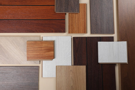 Different samples of wooden flooring on beige background, flat lay