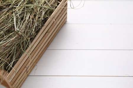 Crate with dried hay on white wooden table, closeup. Space for textの写真素材