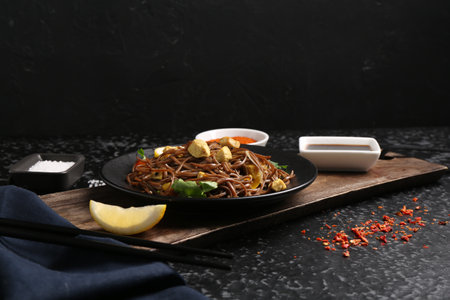 Stir-fry. Tasty noodles with vegetables and meat served on dark textured tableの写真素材