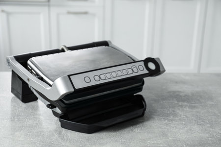Electric grill on gray textured table in kitchen, closeup with space for text. Cooking applianceの写真素材