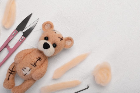 Felted bear, wool, and tools on white table, flat lay. Space for textの写真素材