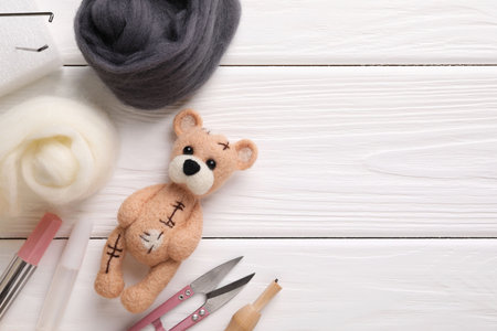 Felted bear, wool and tools on white wooden table, flat lay. Space for textの写真素材