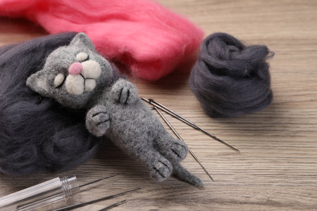 Felted cat, wool and tools on wooden table, closeupの写真素材