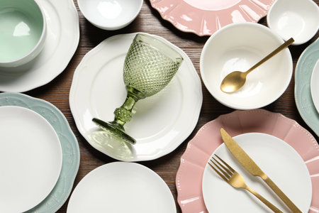 Beautiful ceramic dishware, glass and cutlery on wooden table, flat lay