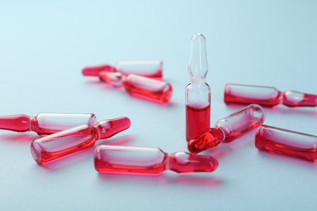 Glass ampoules with liquid on light blue background, closeupの写真素材