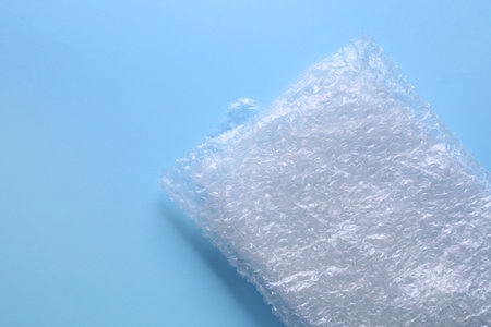Folded transparent   wrap on light blue background, top view. Space for text