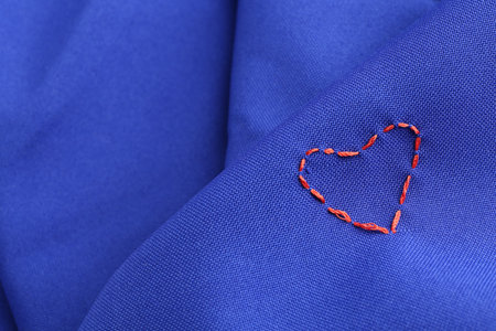 Red embroidered heart on blue cloth, closeup