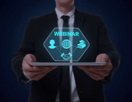 Webinar. Man holding tablet on dark blue background, closeup. Virtual screen with icons over deviceの写真素材