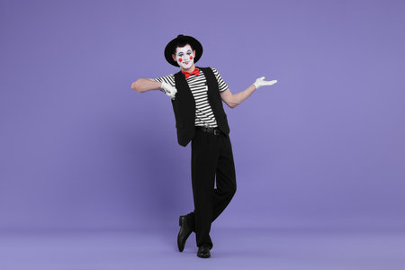 Funny mime artist in hat posing on purple backgroundの写真素材