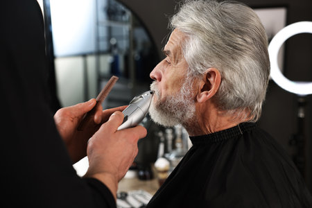 Professional barber trimming client's mustache in barbershopの写真素材