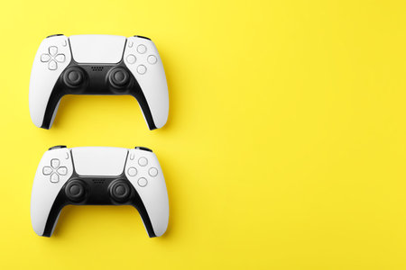 Wireless game controllers on yellow background, flat lay. Space for textの写真素材