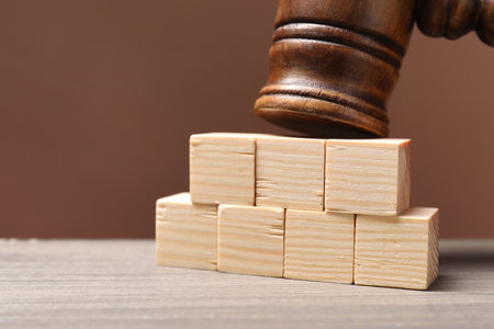 Law. Blank cubes and gavel on wooden table against brown background, closeup. Space for textの写真素材