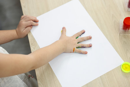 Little girl painting with palm at wooden table, closeupの写真素材