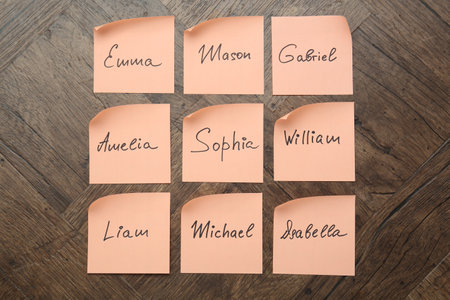 Paper stickers with different names on wooden background, flat lay. Choosing baby's nameの写真素材