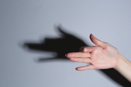 Shadow puppet. Woman making hand gesture like dog on gray background, closeupの写真素材