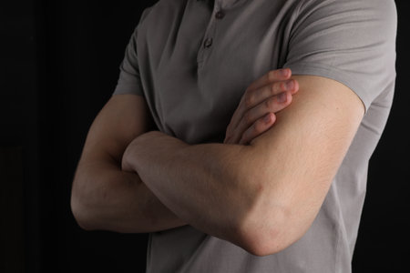 Man with space for tattoo on his arms against black background, closeup