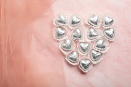 Heart made with delicious chocolate candies on pink background, top view. Space for textの写真素材