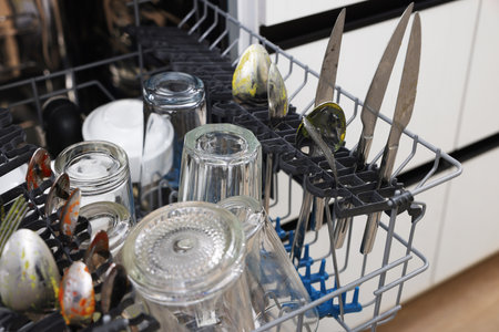 Open modern dishwasher with dirty tableware in kitchen, closeupの写真素材