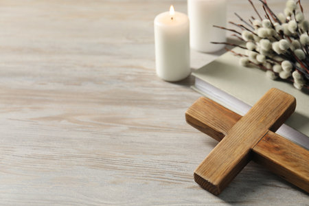 Burning candles, cross, book and willow branches on wooden table. Space for textの写真素材