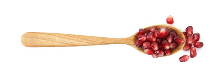 Ripe juicy pomegranate grains in wooden spoon isolated on white, top viewの写真素材
