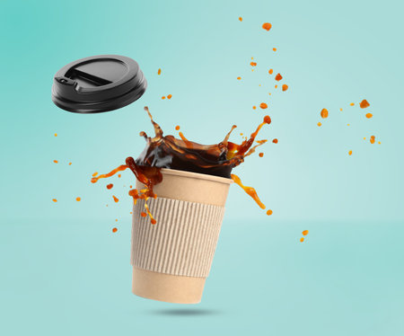 Aromatic coffee in takeaway paper cup in air on turquoise backgroundの写真素材