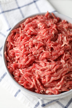 Raw ground meat in bowl on table, closeup