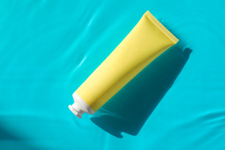 Tube with moisturizing cream in water on light blue background, top viewの写真素材