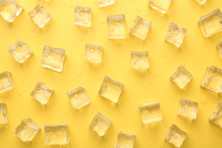 Crystal clear ice cubes on yellow background, flat layの写真素材
