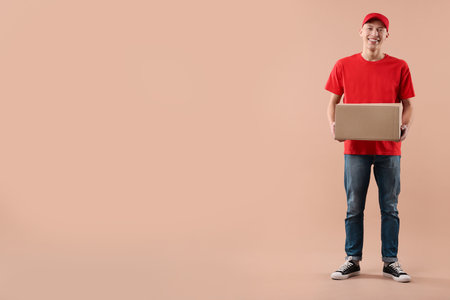 Happy courier with parcel on beige background. Space for textの写真素材