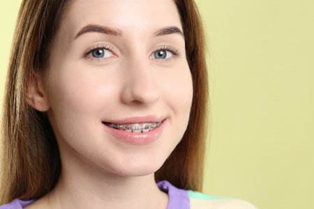 Portrait of smiling woman with dental braces on light green background, closeup. Space for textの写真素材