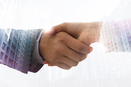 Double exposure of cityscape and partners shaking hands on white background, closeup