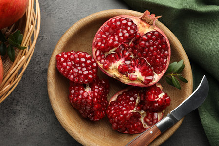 Fresh pomegranates, green leaves and knife on gray table, top viewの写真素材