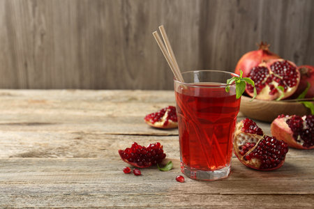 Tasty pomegranate juice in glass and fresh fruits on wooden table. Space for textの写真素材