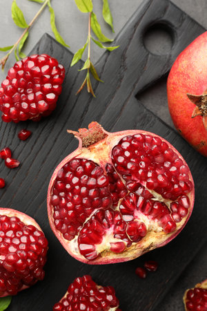 Cut fresh pomegranate and green leaves on gray table, top viewの写真素材