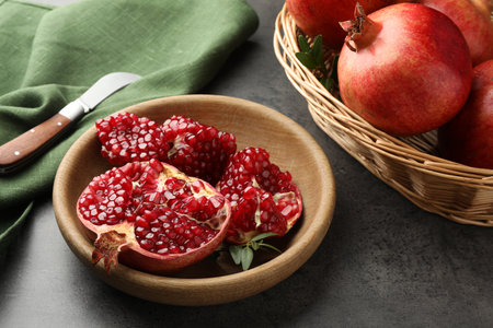 Fresh pomegranates, green leaves and knife on gray tableの写真素材