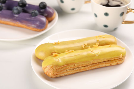 Tasty glazed eclairs on white table, closeupの写真素材