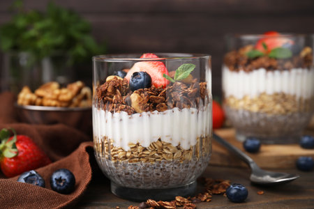 Tasty granola with berries, yogurt and chia seeds in glass on wooden table, closeupの写真素材