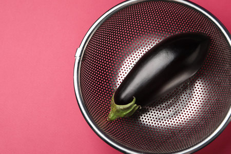 Colander with fresh eggplant on pink table, top view. Space for textの写真素材