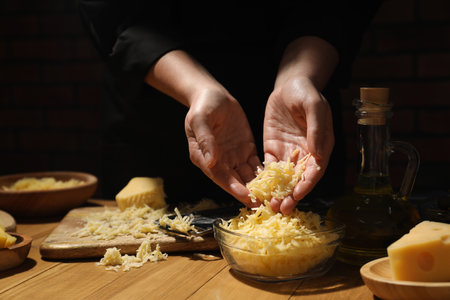 Woman with gratified cheese at wooden table, closeupの写真素材